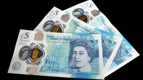 British five-pound notes on a black background